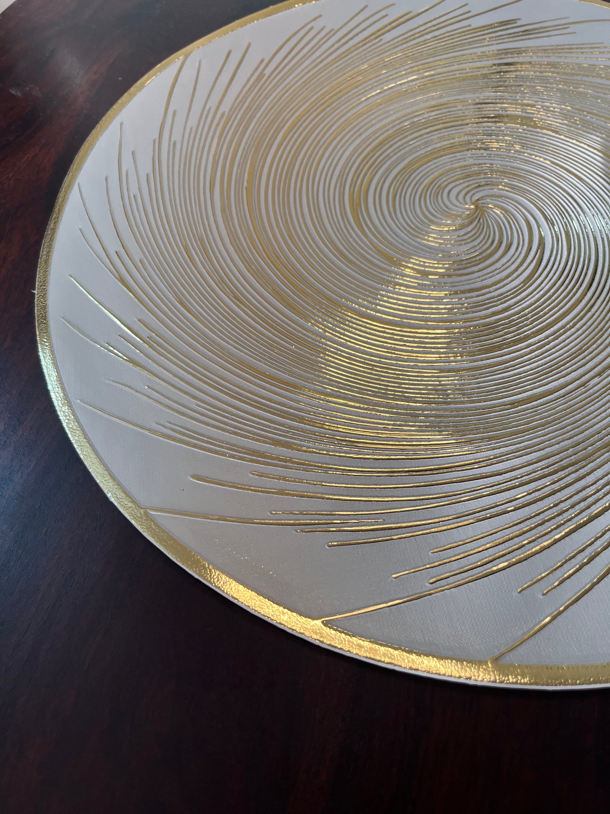 Luxurious dining setup featuring round PVC placemats with a golden spiral design for a sophisticated touch