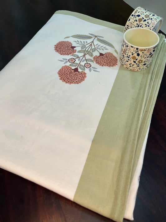 Beautifully styled dining table with a tropical palm and floral print tablecloth in white with a green border