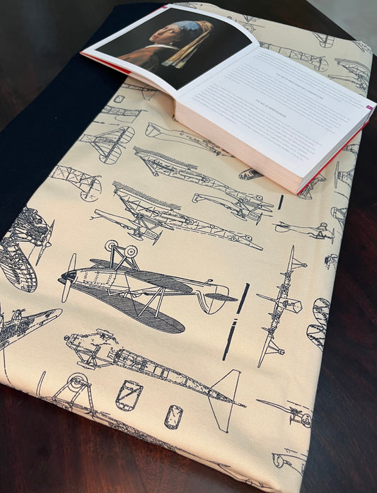 Beautifully styled dining table featuring a vintage aircraft print table cover with an aviation design, navy blue border, and cream background
