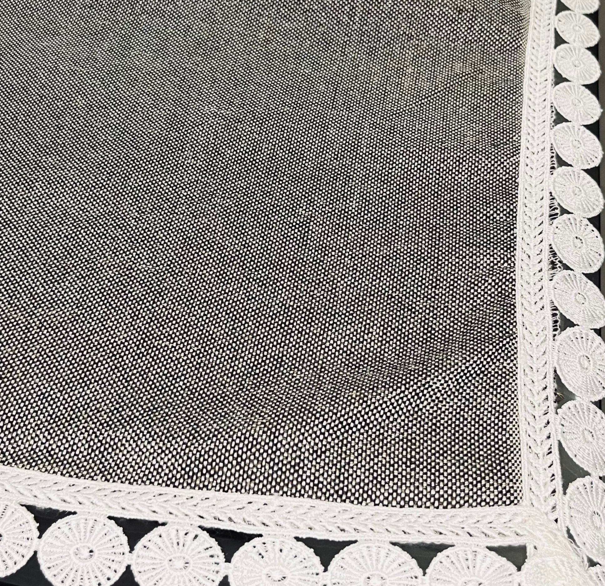 Close-up of dining table cover showcasing grey textured fabric with delicate lace trim and a scalloped white border