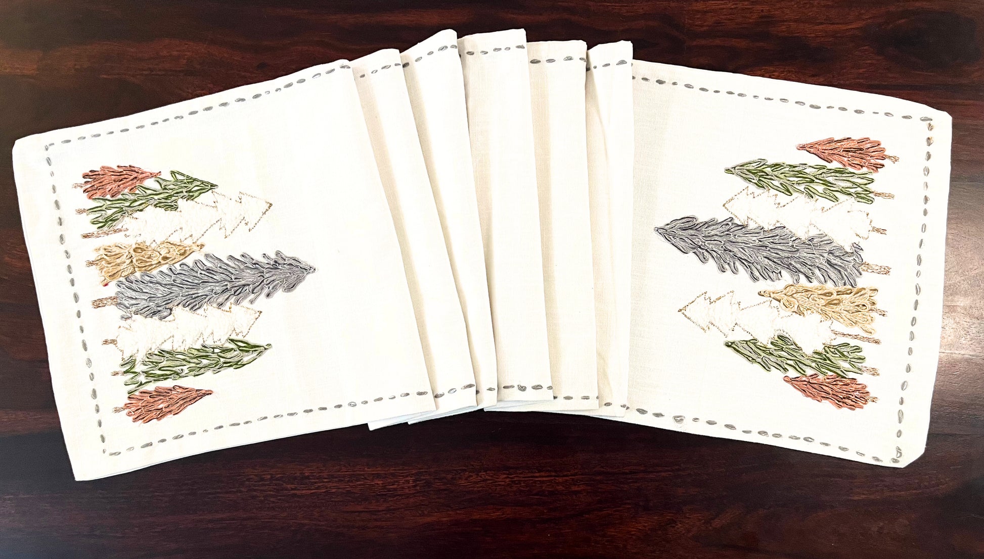 Close-up of decorative table runner showcasing embroidered pine trees with fine detailing