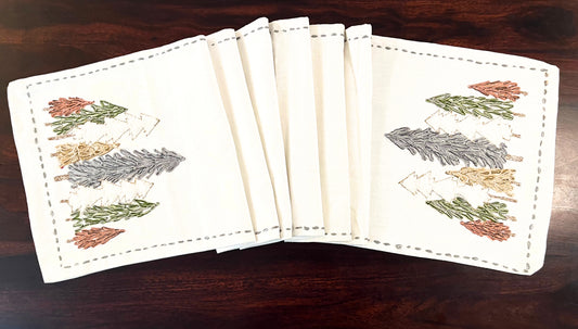 Close-up of decorative table runner showcasing embroidered pine trees with fine detailing