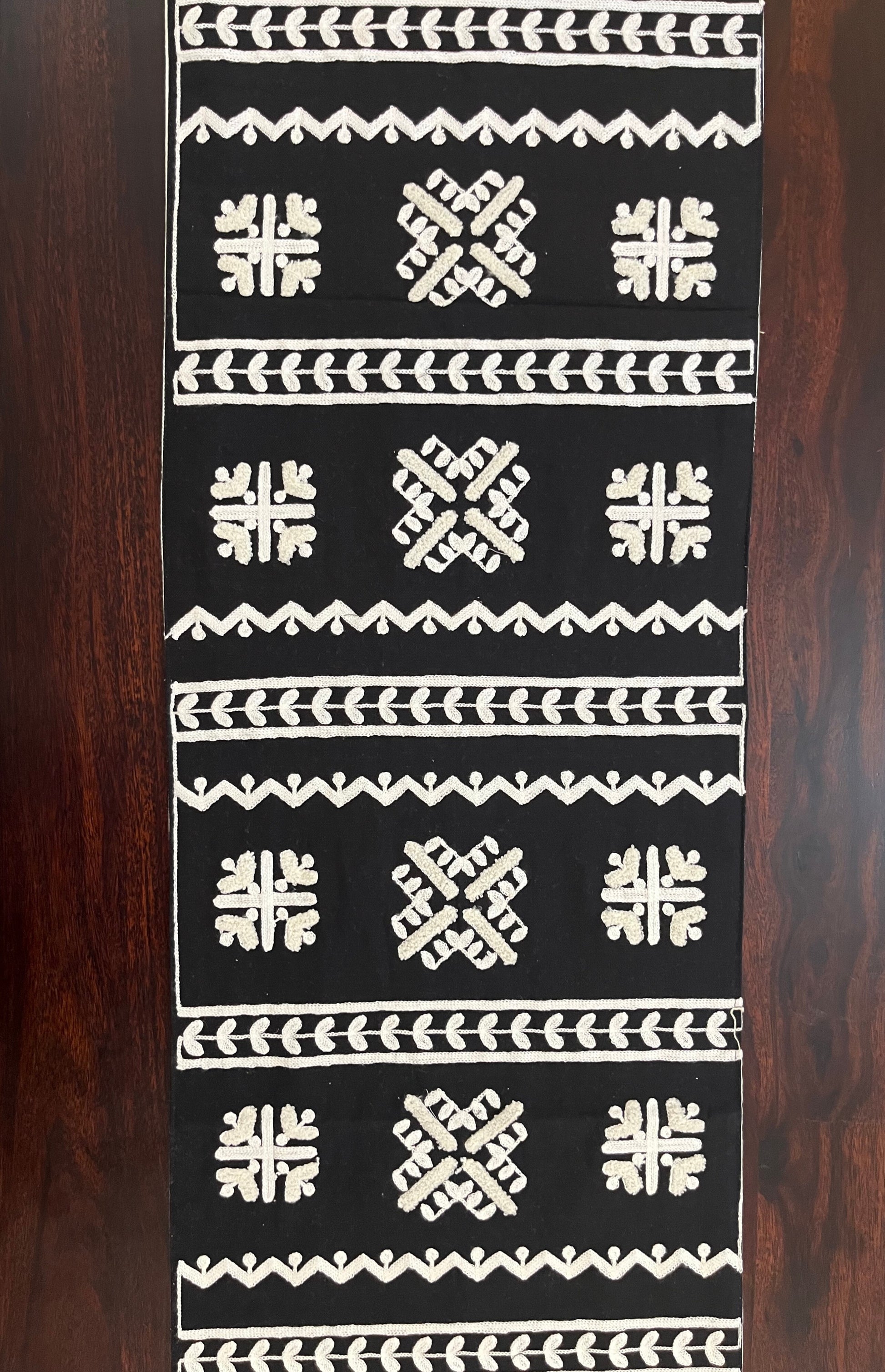 Close-up of decorative table runner showcasing intricate geometric folk embroidery in black and white