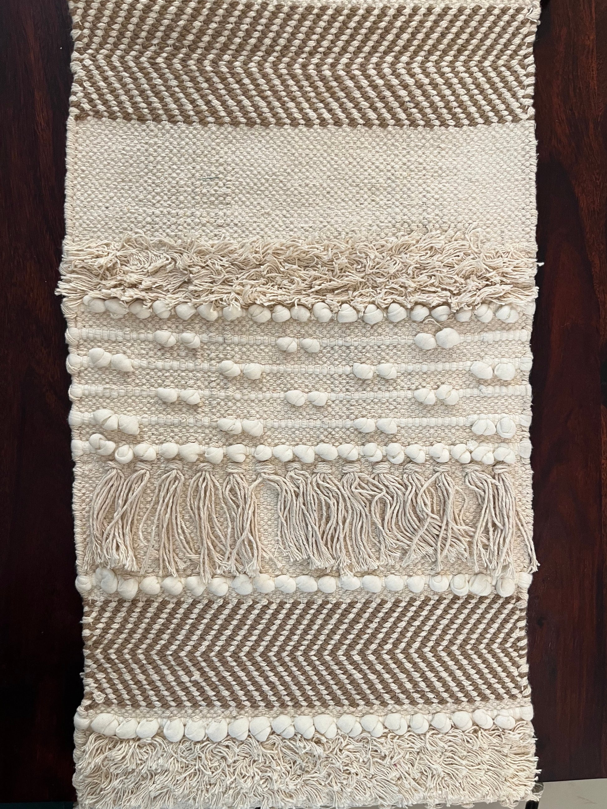 Close-up of decorative table runner showcasing intricate pom poms and tassels
