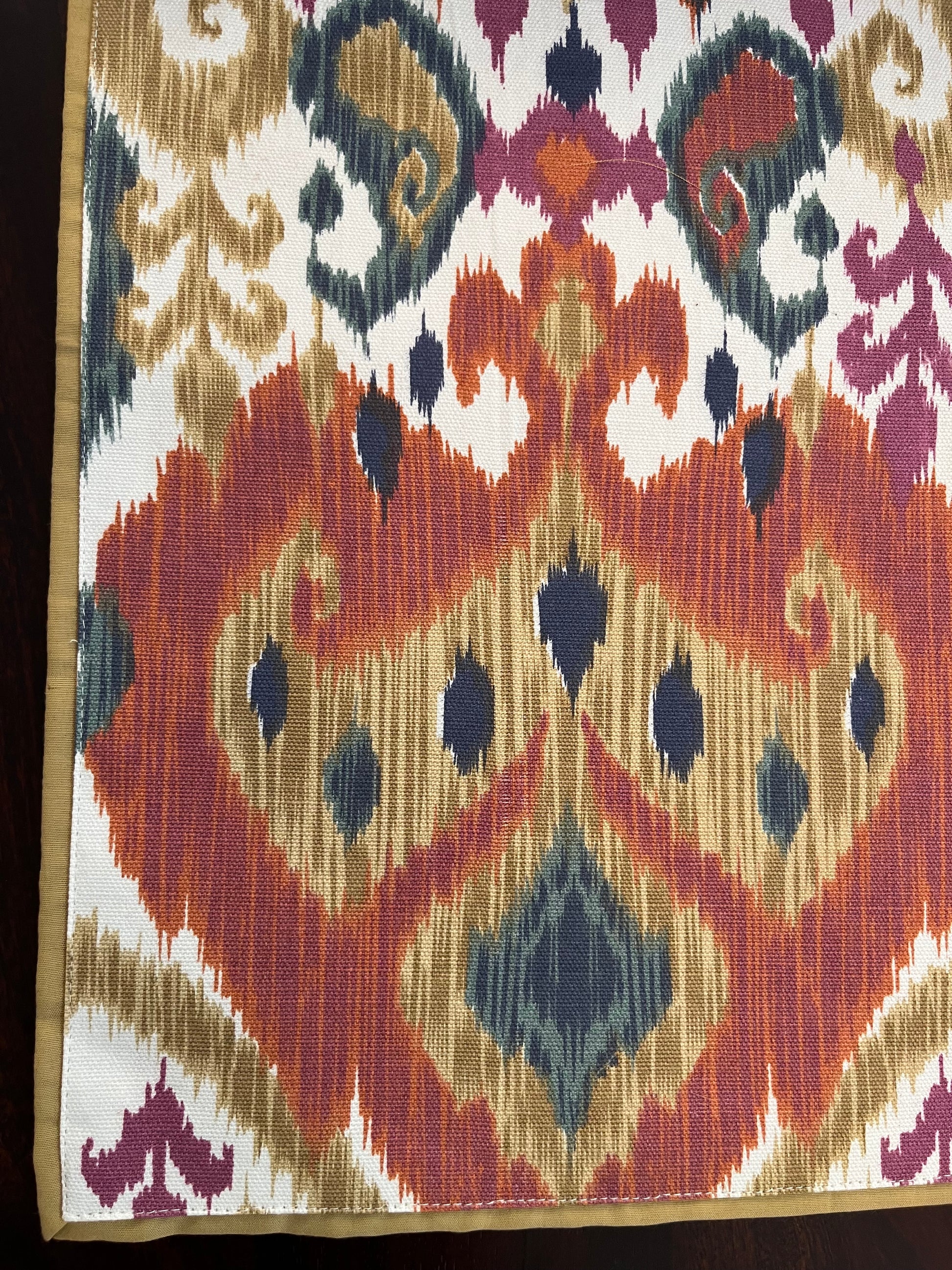 Close-up of decorative table runner showcasing an Ikat pattern with a multicolour boho design in orange and blue