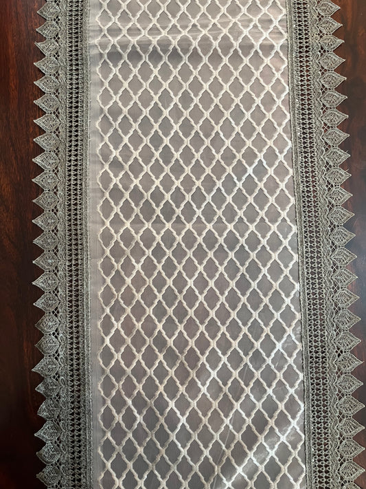 Close-up of elegant lace table runner showcasing a grey diamond pattern with a decorative crochet border