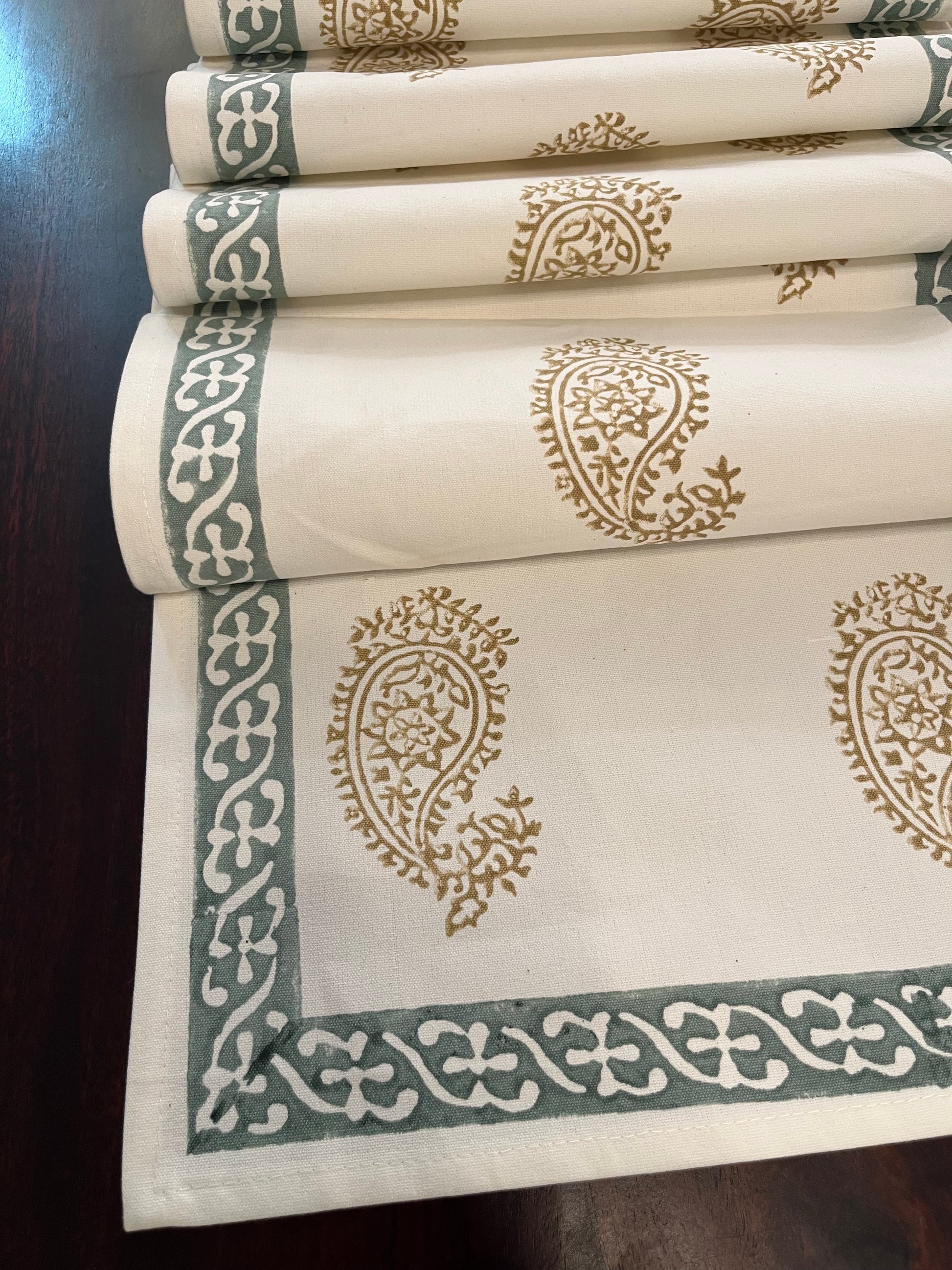 Close-up of table runner showcasing an intricate paisley block print design in golden and sage green