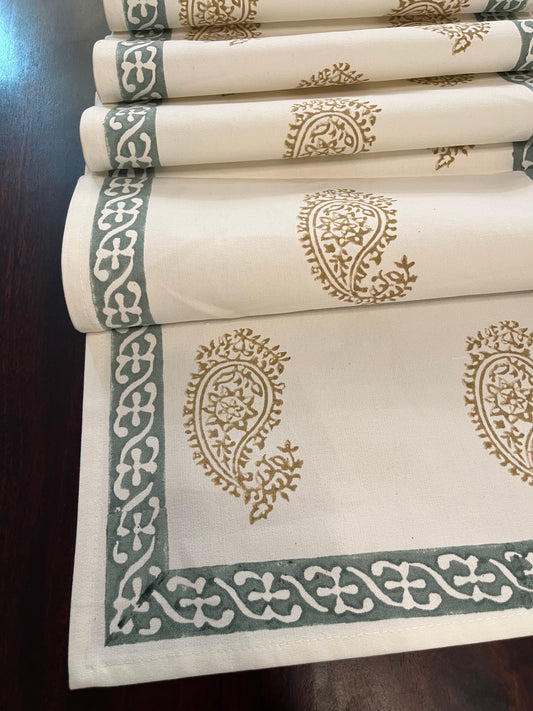 Close-up of table runner showcasing an intricate paisley block print design in golden and sage green