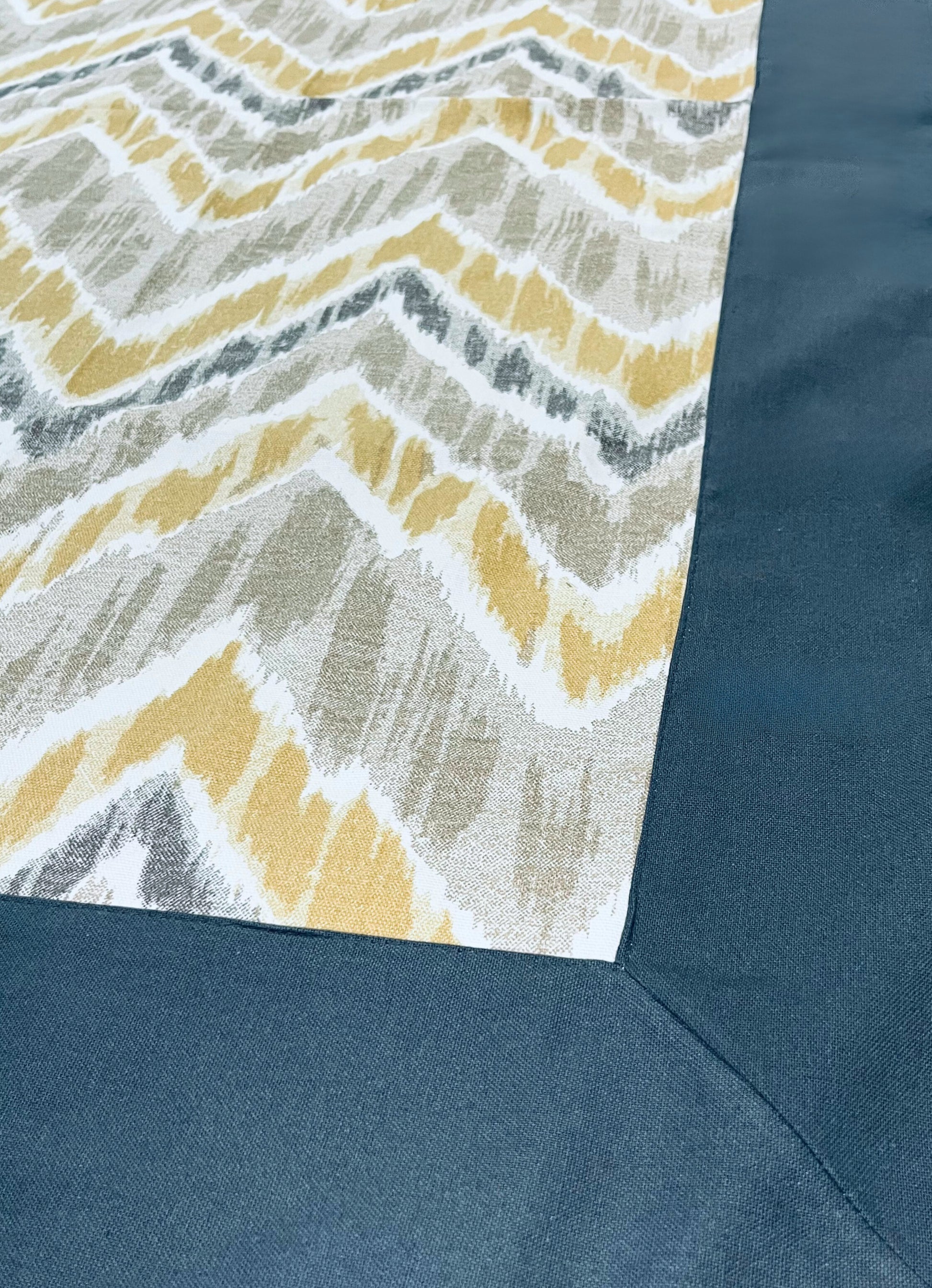 Close-up of chevron pattern dining tablecloth with a modern yellow and grey design and a navy border