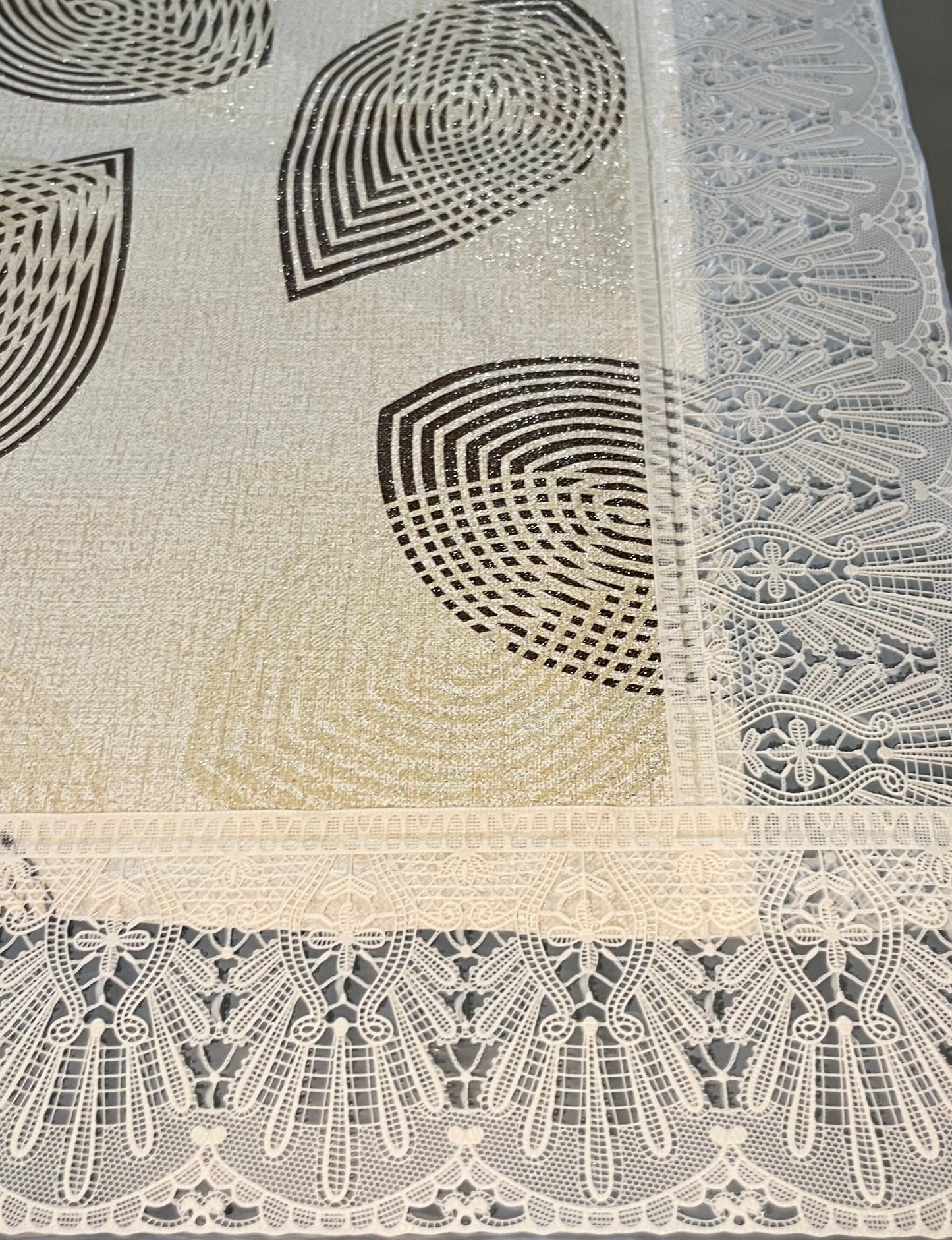 Close-up of elegant PVC dining tablecloth featuring a geometric pattern, lace border, and decorative golden, white, and brown design