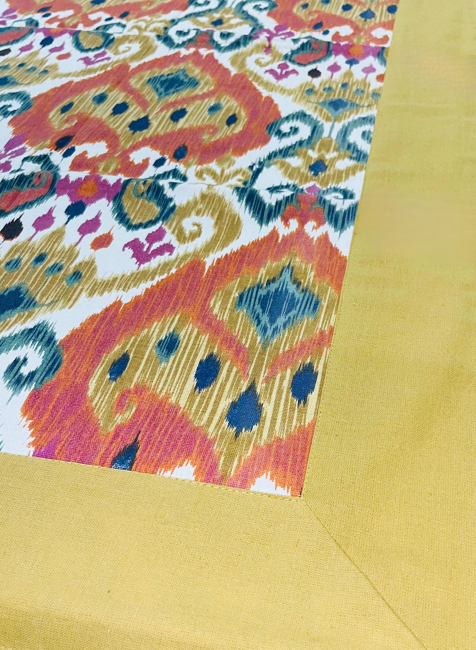 Close-up of decorative dining tablecloth featuring an Ikat pattern with a gold border and modern boho style